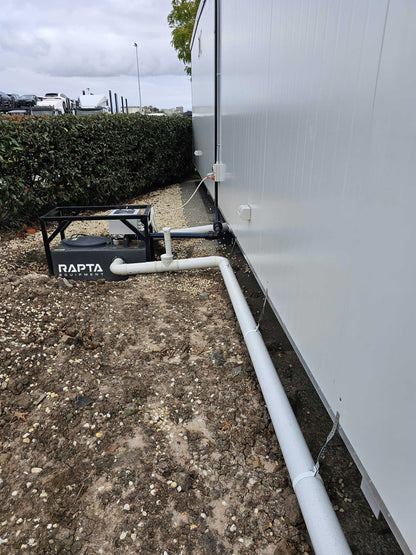 RAPTA CabinPump Ultra connected to a modular building with wastewater inlet and discharge pipework