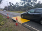 Yellow anti-slip coated RAPTA road plate carrying live traffic over a road excavation
