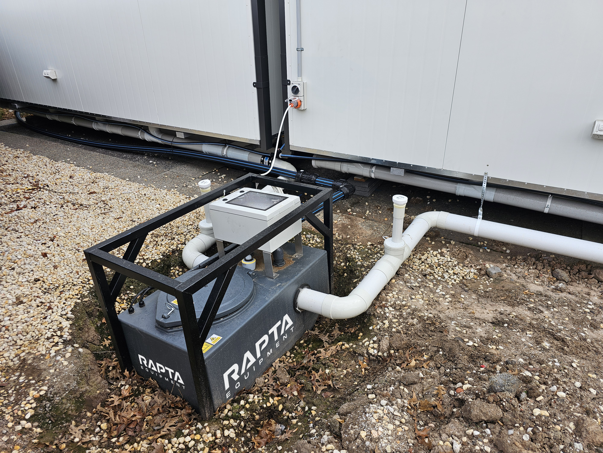 RAPTA CabinPump Ultra wastewater system installed and connected beside a modular site building