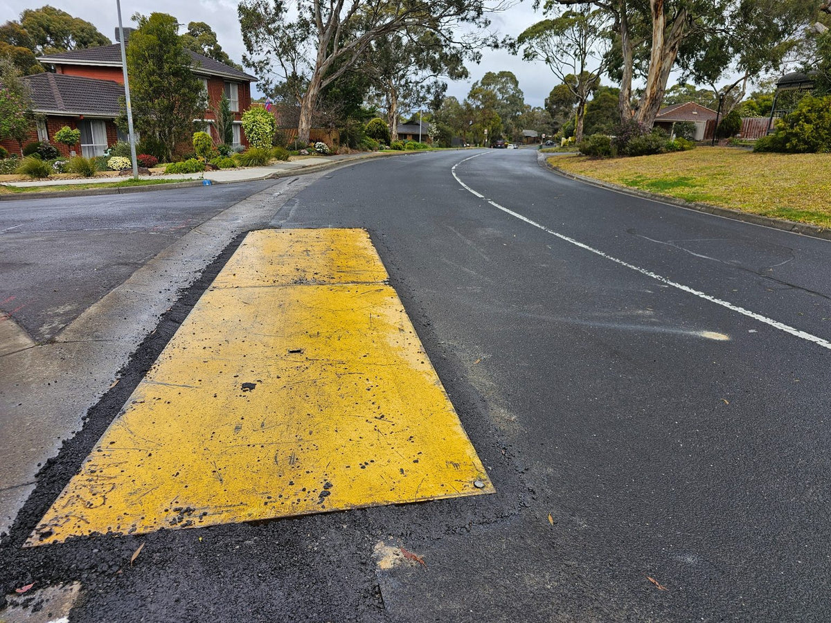 Yellow anti-slip RAPTA steel road plate installed on a road.