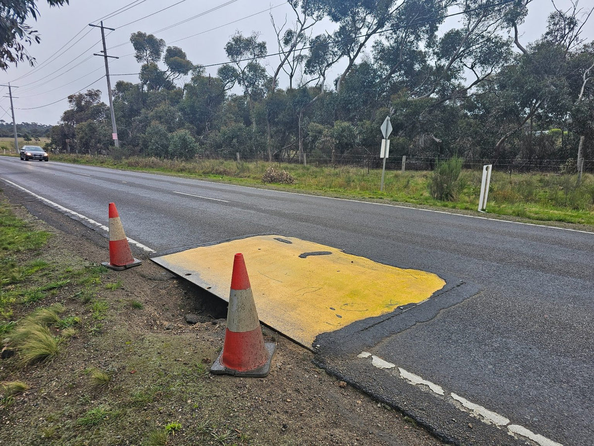 Yellow anti-slip RAPTA steel road plate covering a roadside excavation.