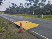 Yellow anti-slip RAPTA steel road plate covering a roadside excavation.