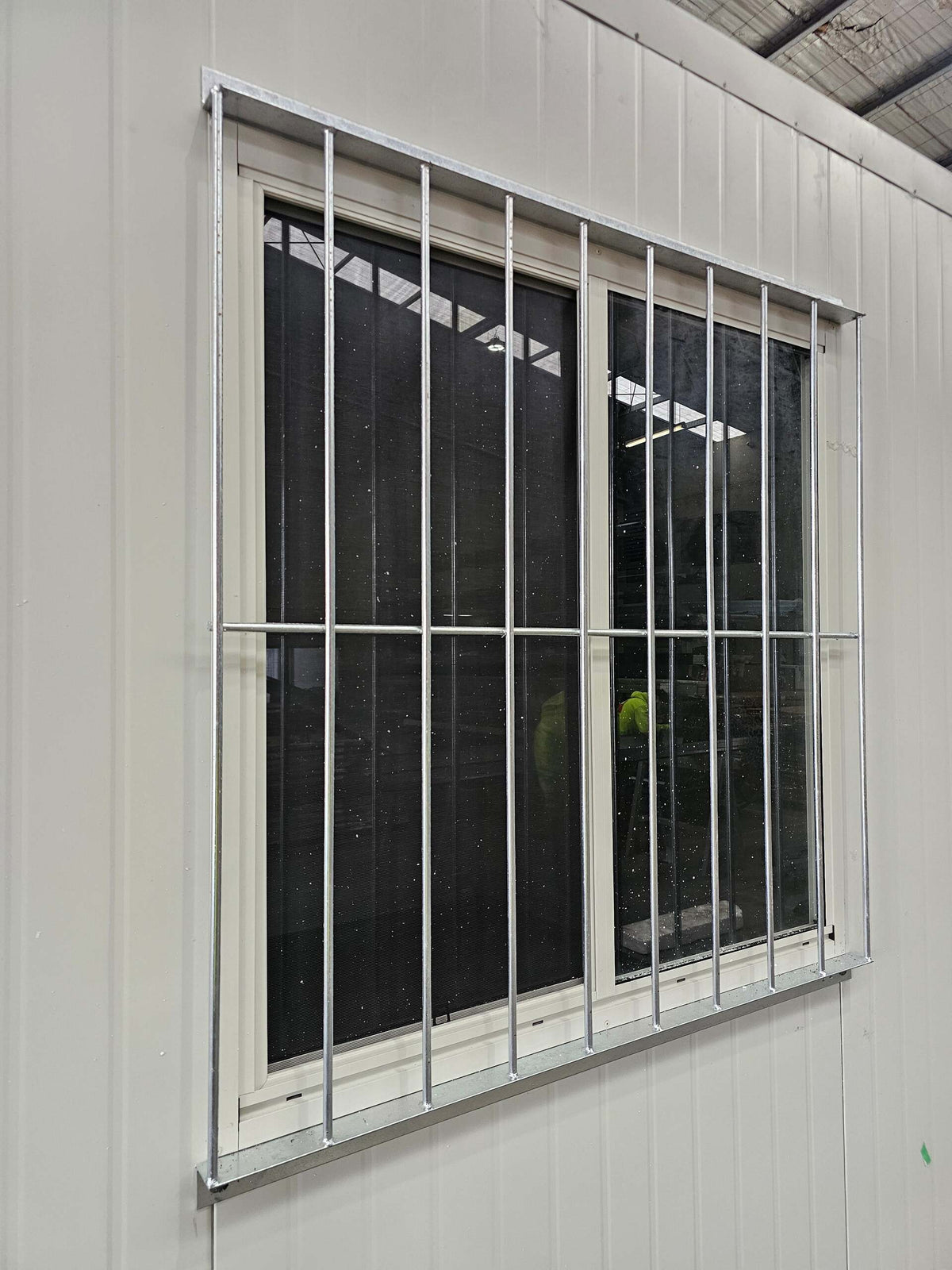 RAPTA 1250 x 1260mm galvanised window security grill installed on a portable building, angled view